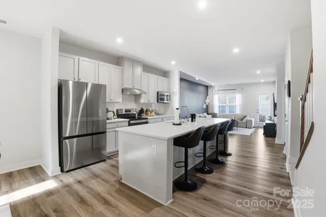 a kitchen with stainless steel appliances granite countertop a stove a refrigerator and a white cabinets