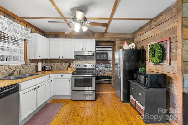 a kitchen with stainless steel appliances kitchen island granite countertop a sink cabinets and wooden floor