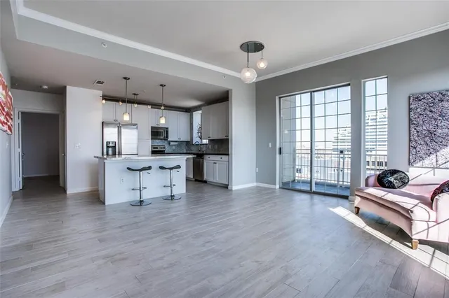 a view of an empty room with kitchen and hardwood floor