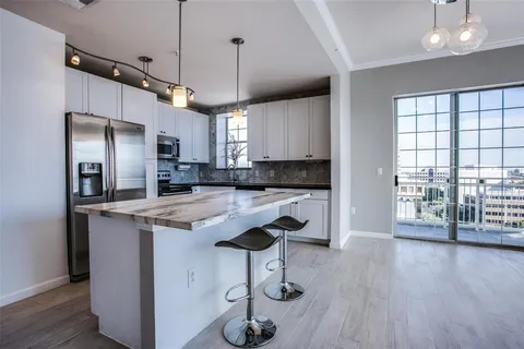 a kitchen with stainless steel appliances granite countertop a refrigerator a sink dishwasher a stove and white cabinets with wooden floor