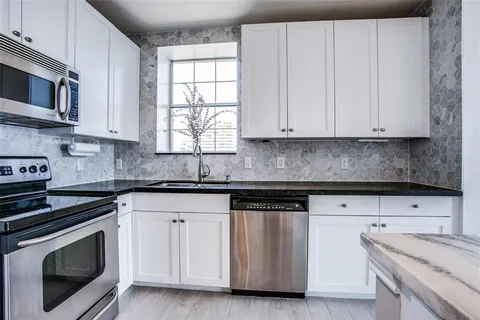 a kitchen with granite countertop white cabinets and a stove a sink