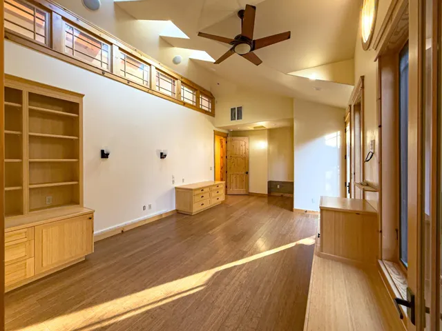 a view of a hallway with wooden floor and a ceiling fan