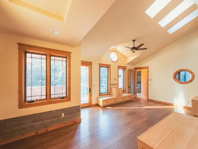 a view of an empty room with a window and wooden floor