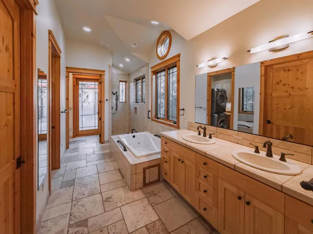a spacious bathroom with a double vanity sink a mirror and a shower