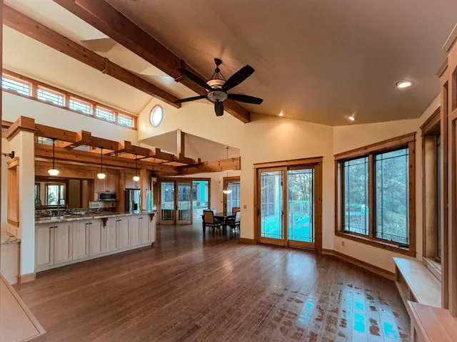 a view of a big room with wooden floor a ceiling fan and windows
