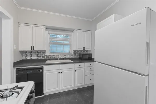 a kitchen with white cabinets and sink