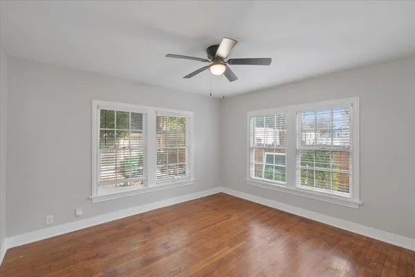 a view of an empty room with a window and wooden floor