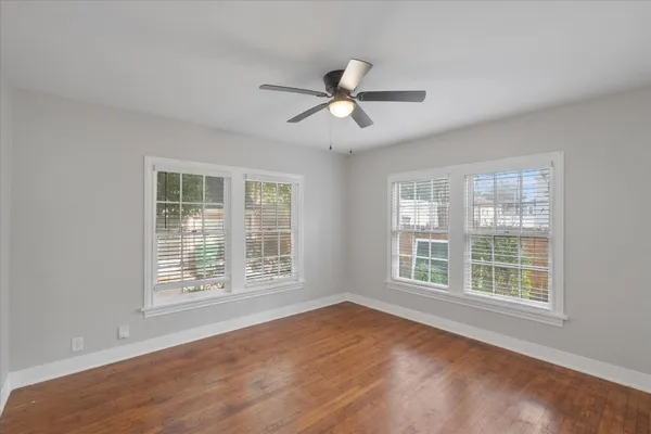 a view of an empty room with a window and wooden floor