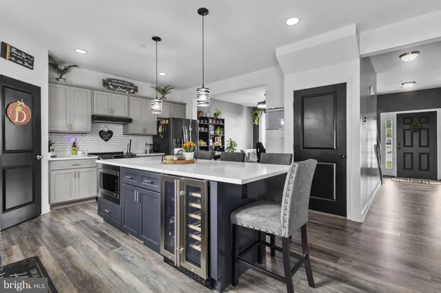 a kitchen with stainless steel appliances kitchen island granite countertop a table chairs and a refrigerator