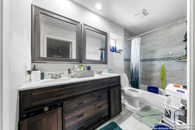 a bathroom with a granite countertop sink mirror vanity bathtub and a toilet