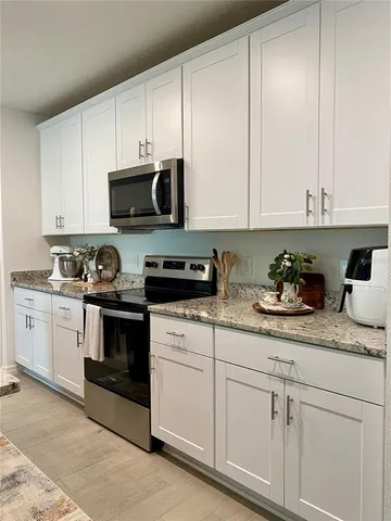 a kitchen with granite countertop white cabinets and white appliances