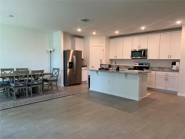 a kitchen with stainless steel appliances kitchen island granite countertop a table and chairs in it