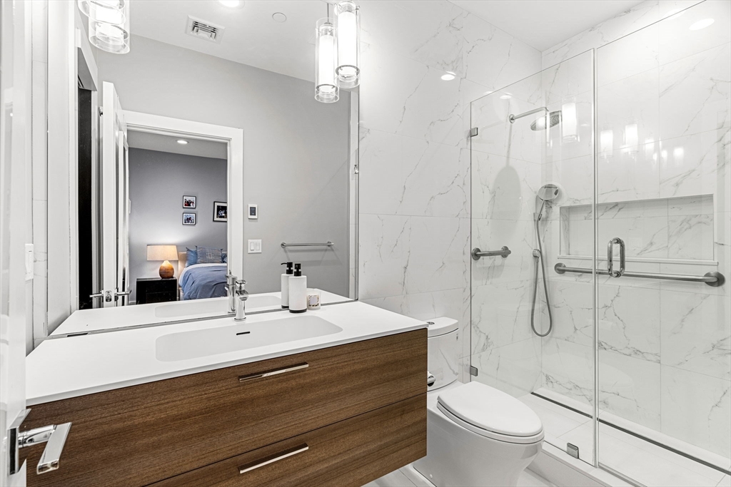 39 A Street, Unit 4 Boston, MA 02127 - Photo 15 of 28 a bathroom with a double vanity sink toilet mirror and shower