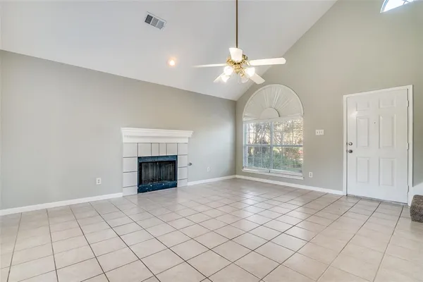 a view of an empty room with chandelier fan and fire place