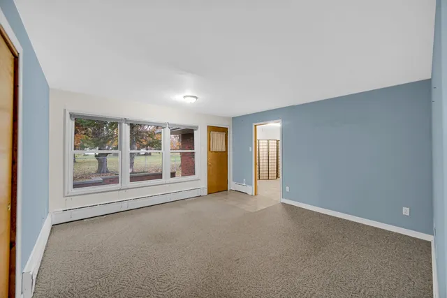 an empty room with a fireplace and large window
