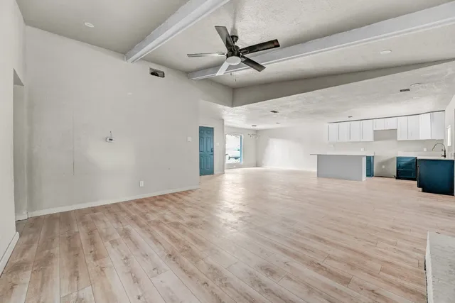 a view of empty room with wooden floor and ceiling fan