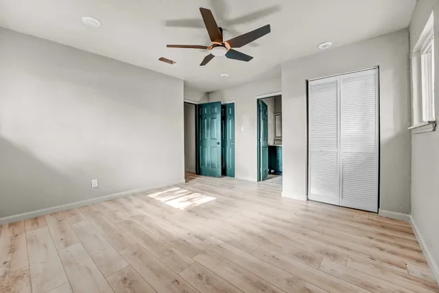 an empty room with wooden floor and a ceiling fan