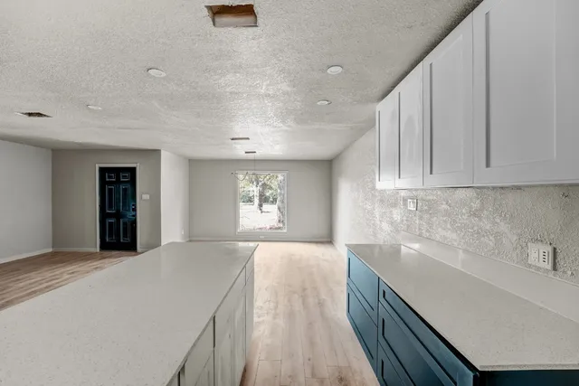 a large white kitchen with sink and natural light