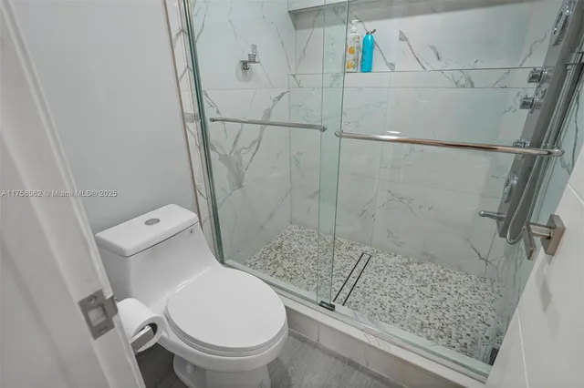 a white toilet sitting next to a bath tub and a shower