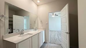 4304 Placer Mine Road Aubrey, TX 76227 - Photo 8 of 12 Dual integrated sinks set into a vanity with white cabinetry and an expansive mirror