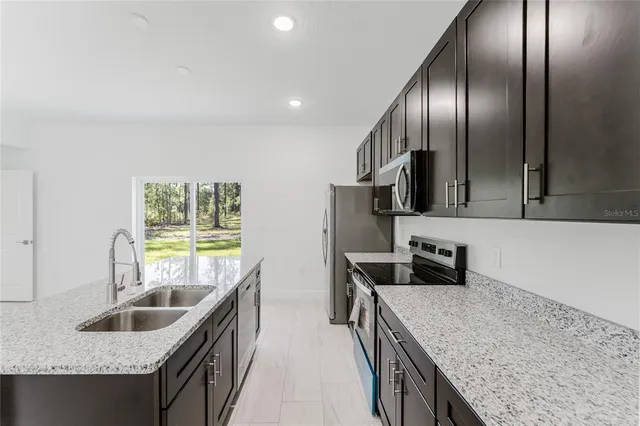 a kitchen with stainless steel appliances granite countertop a sink a stove and a refrigerator