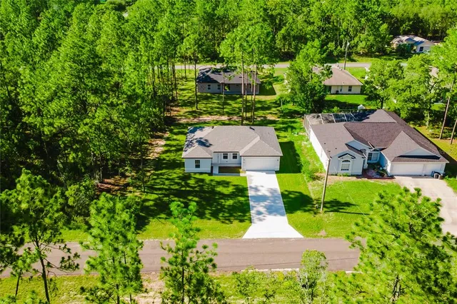 an aerial view of residential house with outdoor space and trees all around