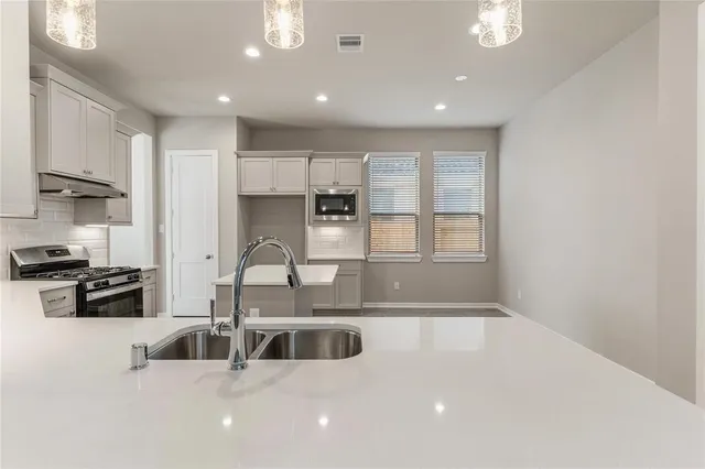 a kitchen with stainless steel appliances granite countertop a sink a stove and a refrigerator