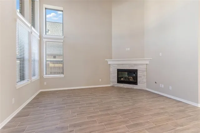 a view of an empty room with wooden floor fireplace and a window
