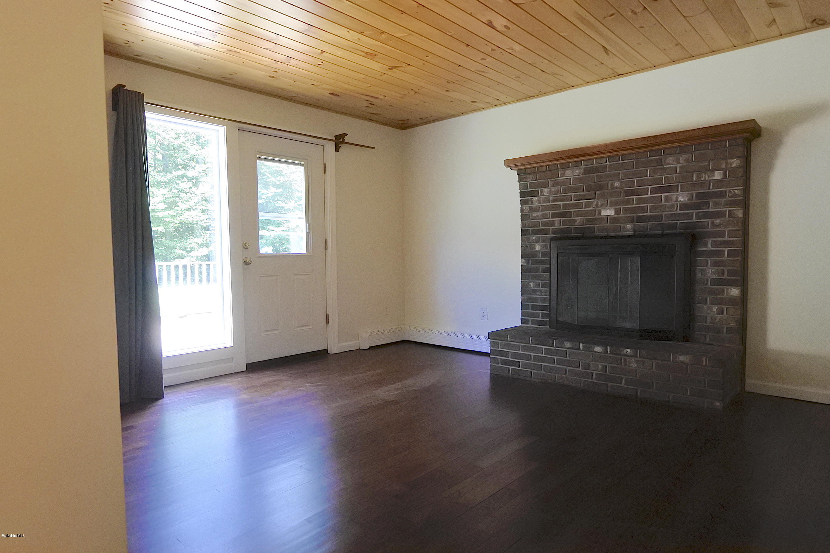 24 Housatonnuck Road Stockbridge, MA 01262 - Photo 12 of 36 an empty room with wooden floor fireplace and windows