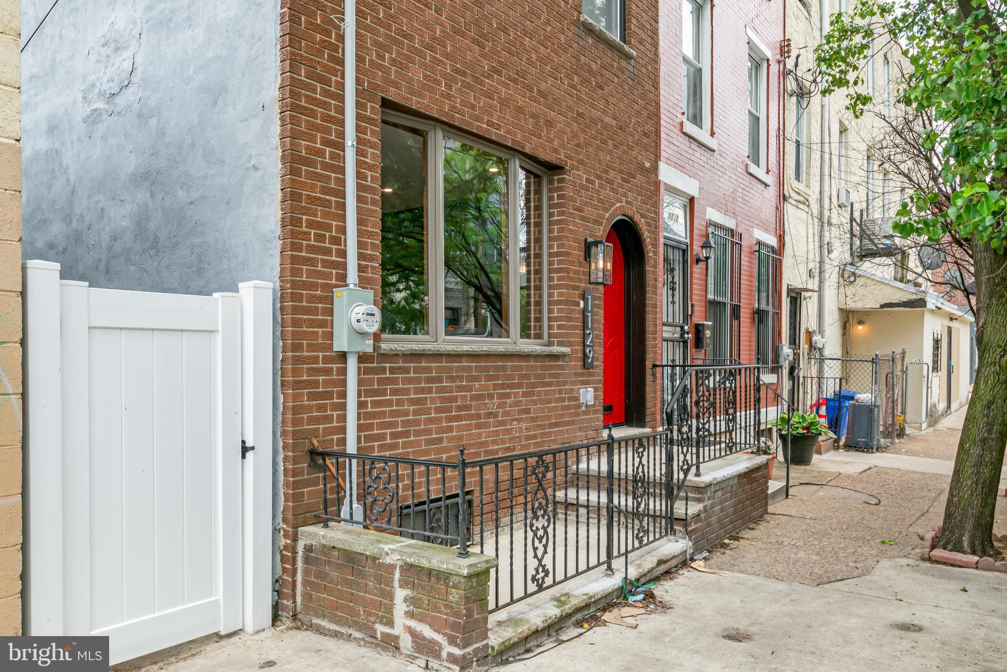 1129 South 12th Street Philadelphia, PA 19147 - Photo 24 of 24 a view of a brick house with large windows and wooden fence