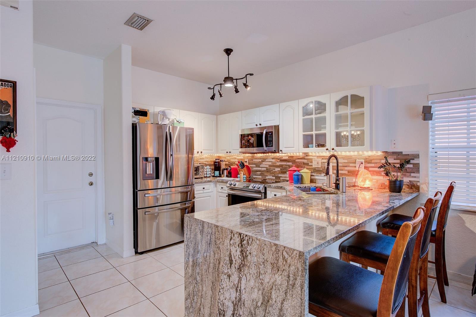 18226 Southwest 145th Avenue Miami, FL 33177 - Photo 11 of 30 a kitchen with stainless steel appliances granite countertop a dining table and chairs