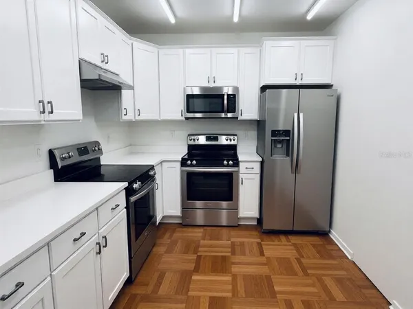 a kitchen with white cabinets and stainless steel appliances