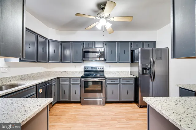 a kitchen with stainless steel appliances granite countertop hardwood floor sink stove and refrigerator