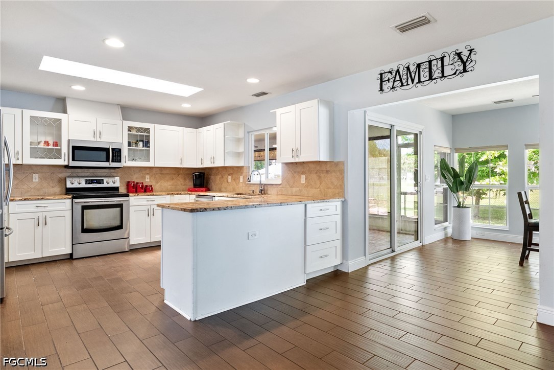 17290 Rewis Road Alva, FL 33920 - Photo 2 of 50 a kitchen with stainless steel appliances granite countertop a refrigerator a stove top oven a sink dishwasher and white cabinets with wooden floor