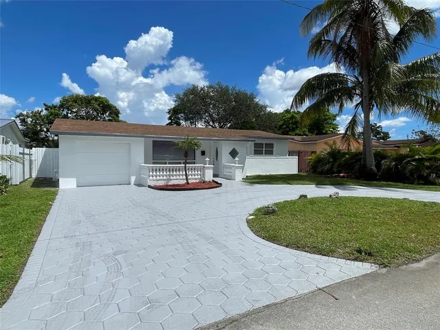 a front view of a house with a garden and palm tree