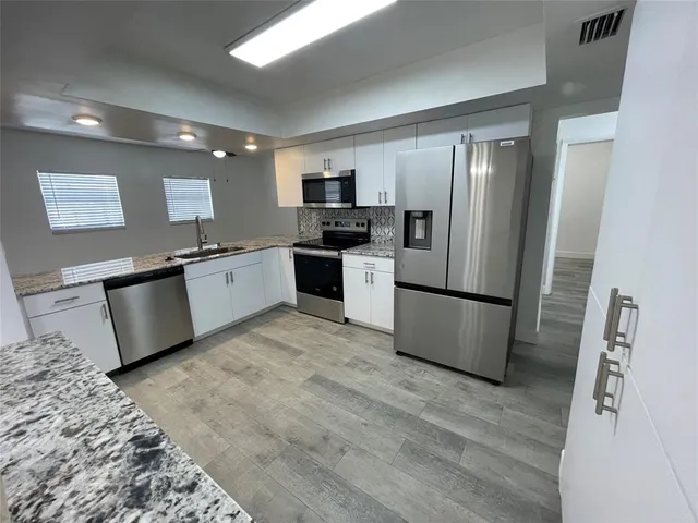 a kitchen with stainless steel appliances granite countertop a refrigerator sink and stove
