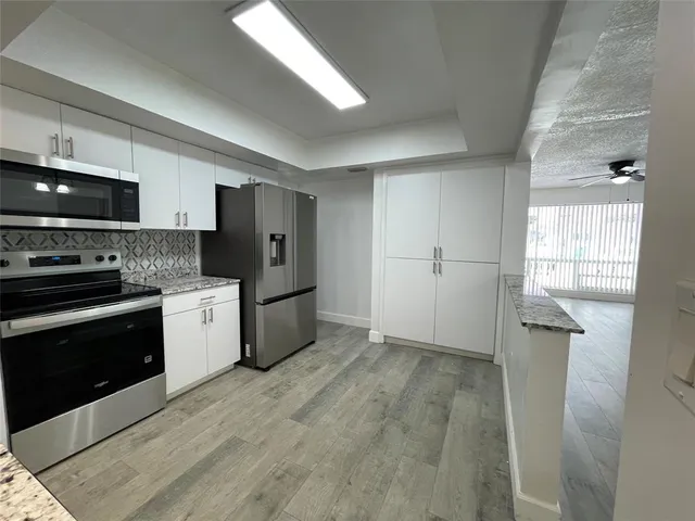 a kitchen with granite countertop a refrigerator and a stove top oven