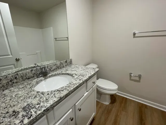 a bathroom with a granite countertop sink a toilet and a mirror