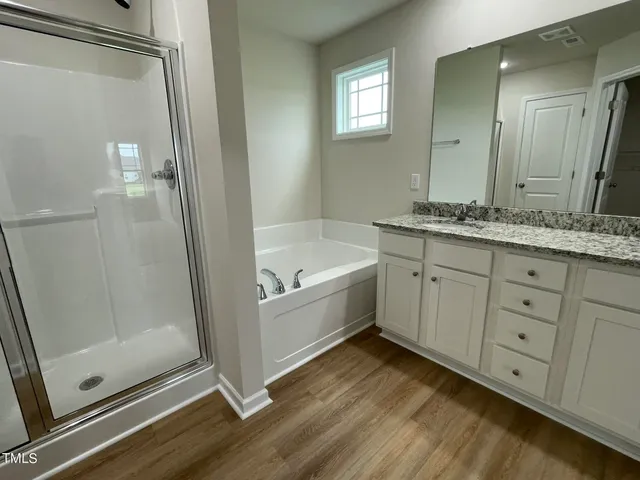 a bathroom with a granite countertop sink a mirror and a bathtub
