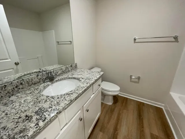 a bathroom with a granite countertop sink a toilet and a mirror