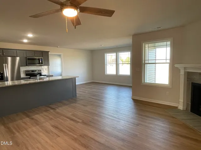 a kitchen with stainless steel appliances granite countertop a sink a stove top oven a refrigerator with wooden floors and a fireplace