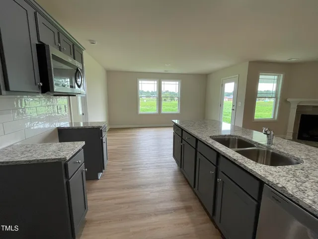 a large kitchen with granite countertop a sink and a wooden floor
