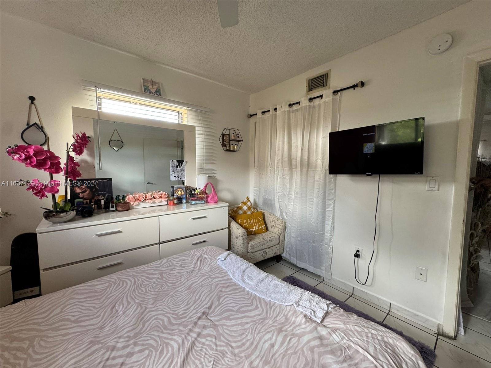 231 East 7th Street Hialeah, FL 33010 - Photo 39 of 39 a bedroom with a bed a flat screen tv and a couch