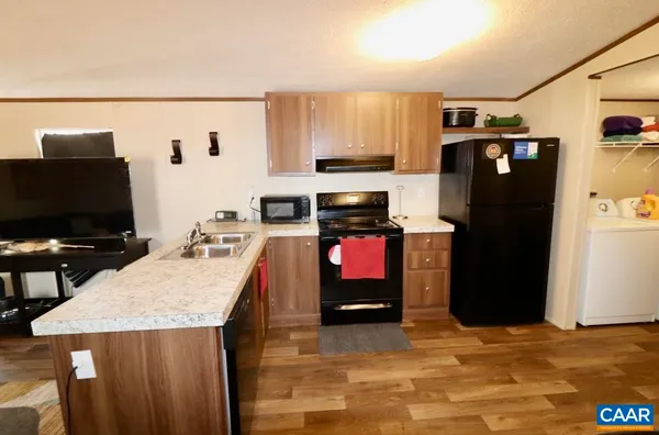 a kitchen with stainless steel appliances granite countertop a refrigerator a stove and a sink with wooden floor