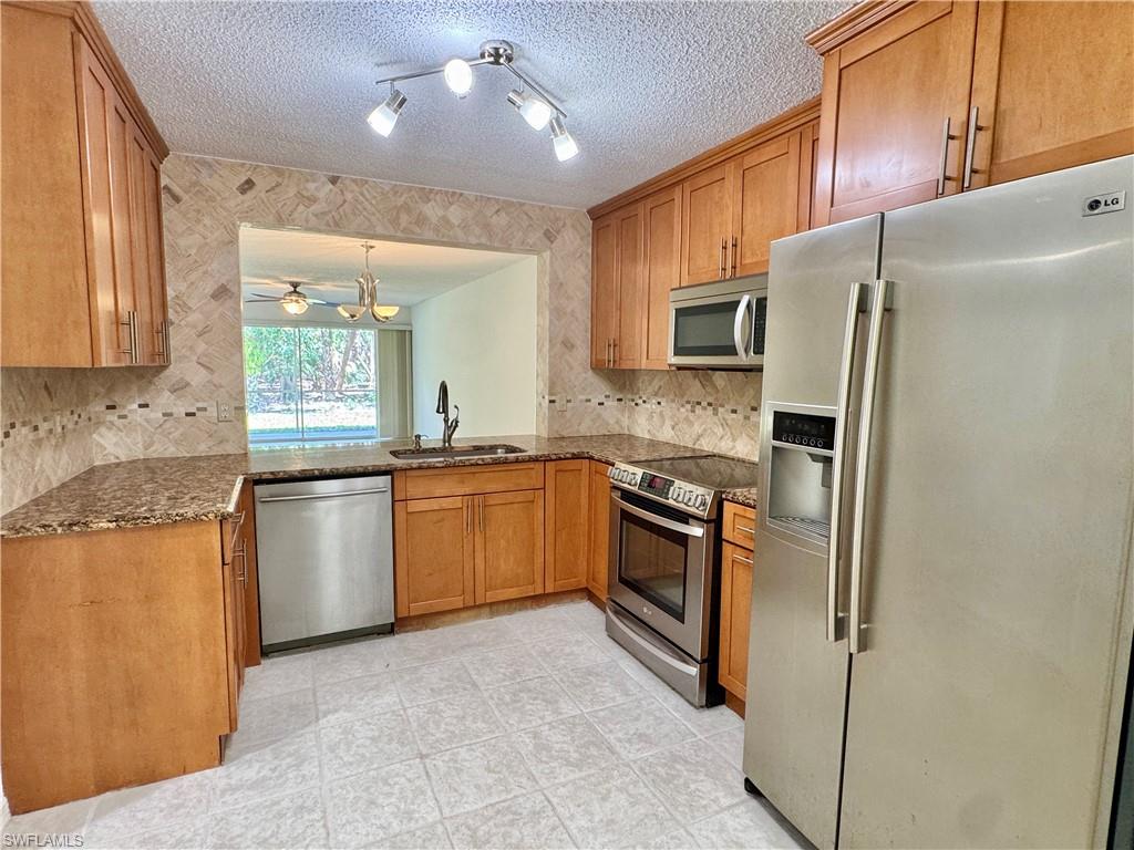 661 Squire Circle, Unit 101 Naples, FL 34104 - Photo 3 of 25 a kitchen with stainless steel appliances granite countertop a refrigerator and a stove top oven