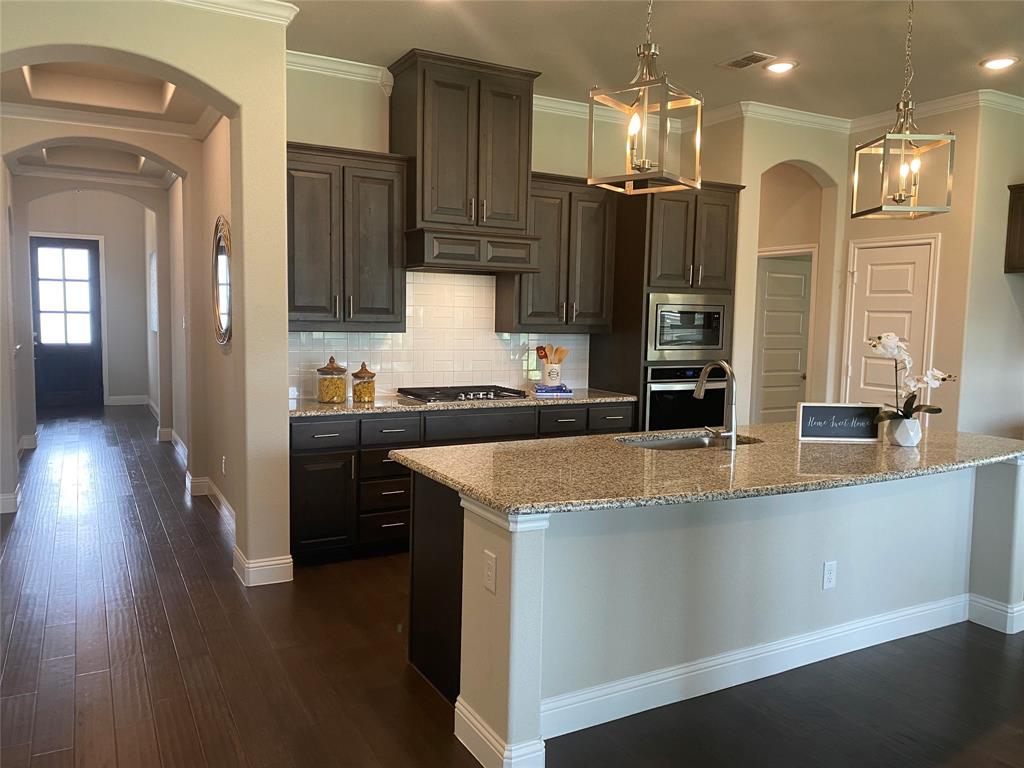 209 Johnson Street Granbury, TX 76048 - Photo 6 of 40 Kitchen with backsplash, stainless steel appliances, dark hardwood / wood-style flooring, and a kitchen island with sink