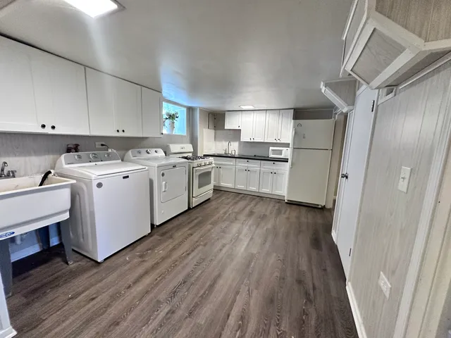 a white cabinets a sink a stove and a refrigerator in a kitchen