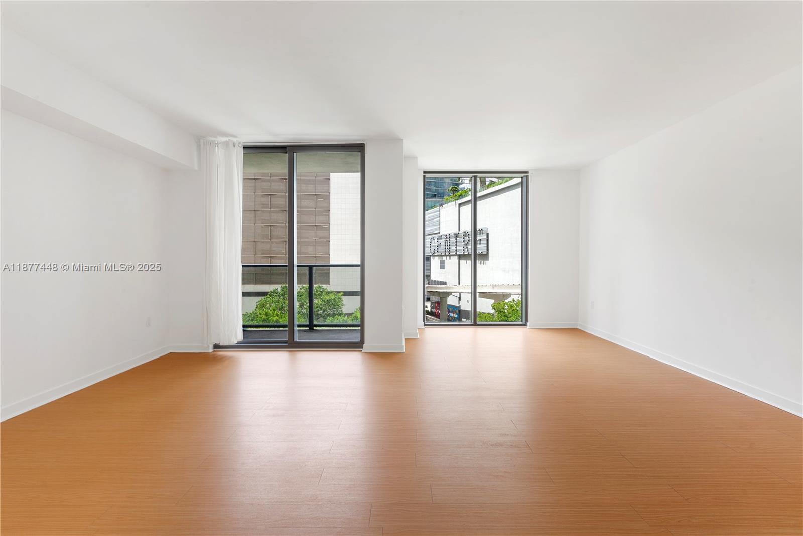 31 Southeast 6th Street, Unit 705 Miami, FL 33131 - Photo 3 of 12 an empty room with wooden floor and windows
