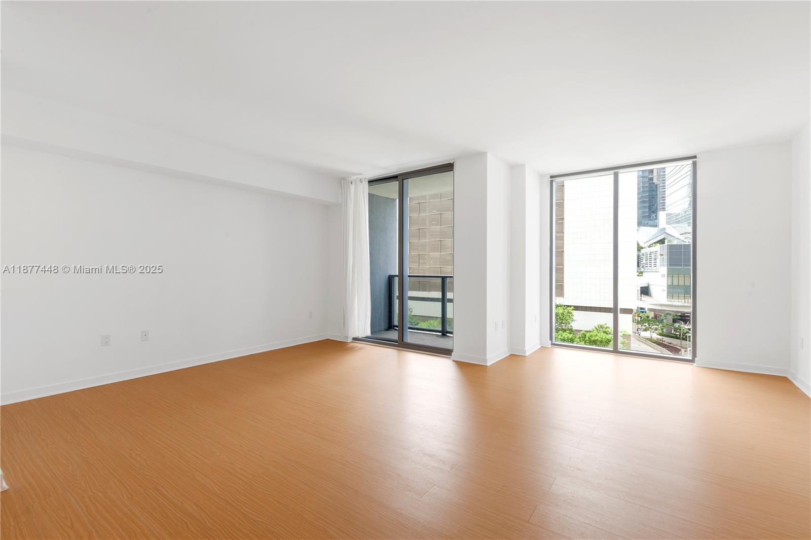 31 Southeast 6th Street, Unit 705 Miami, FL 33131 - Photo 9 of 12 an empty room with wooden floor and windows