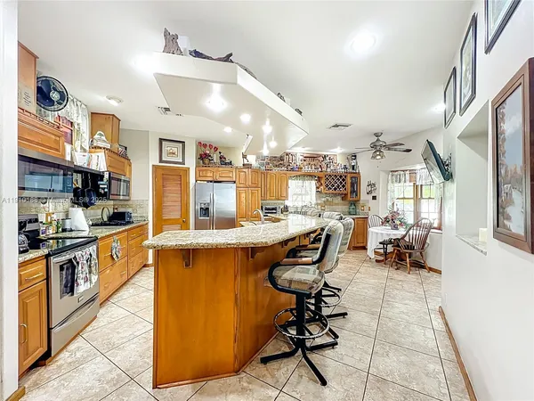 a kitchen with stainless steel appliances kitchen island granite countertop a table chairs and a refrigerator
